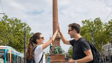 Zwei Personen geben High-Five neben Denkmal.