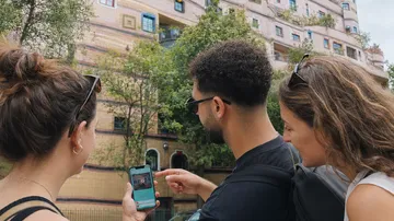Drei Personen betrachten Handy im Freien.