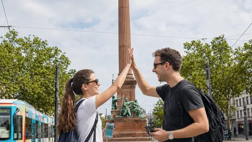 Zwei Menschen geben High-Five bei einem Denkmal.