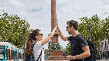 Two friends high-five near a monument.