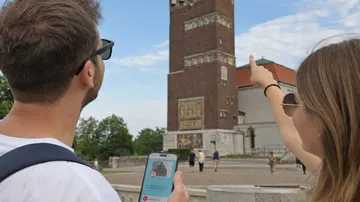 Zwei Personen betrachten hohen Backsteinturm.