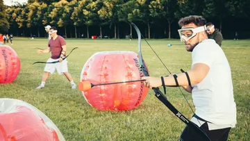 Menschen spielen Bogenschießen im Park.