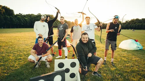 Group of men practicing archery in a park.