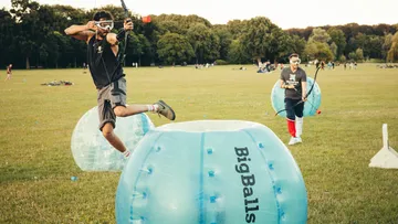 People playing archery tag in a park.
