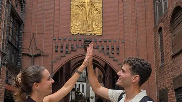 Zwei Personen geben sich High-Five an Ziegelbogen.