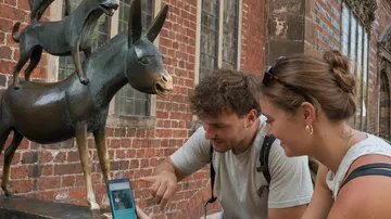 Two people looking at statue in city.