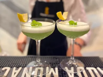 Zwei Cocktails stehen auf der Theke, garnierte mit Basilikum.