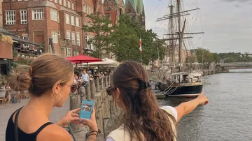 Zwei Personen betrachten Schiff im Hafen.