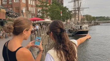 Zwei Frauen betrachten ein Schiff im Fluss.