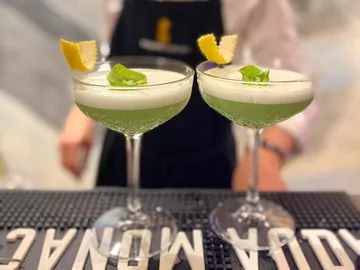 Zwei Cocktails stehen auf der Theke, grün und dekoriert.