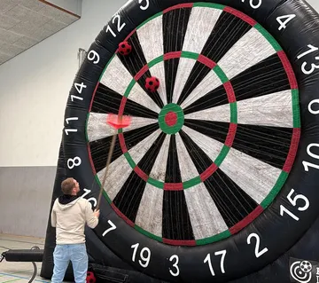 Person schießt Ball auf große Dartscheibe.