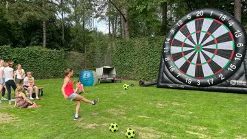 Frau kickt Ball auf aufblasbare Dartscheibe draußen.