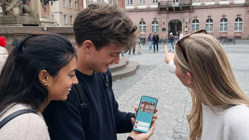Personen nutzen Handy-App auf Stadtplatz.