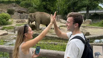 Zwei Personen geben sich High-Five am Elefantengehege.