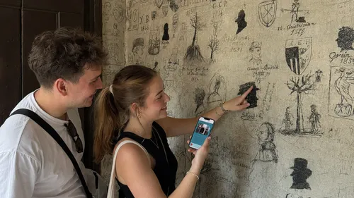 Two people examine graffiti-covered wall.