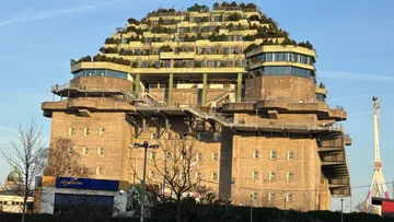 Betongebäude mit Dachgarten, klarer Himmel.