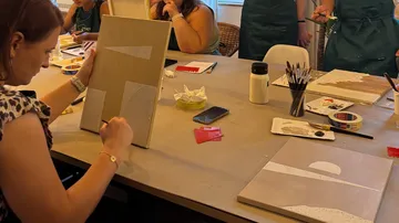 People painting at an art workshop table.