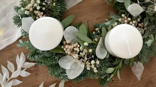 Two white candles on green wreath.