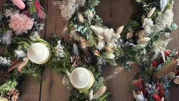 Christmas wreaths with candles on wooden table.