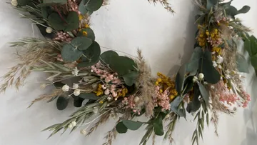 Floral wreath with dried flowers on wall.