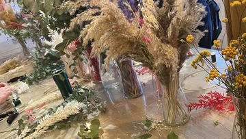 Getrocknete Blumenarrangements auf Holztisch.