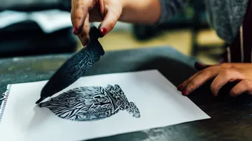 Hand lifting stamp from printed paper.