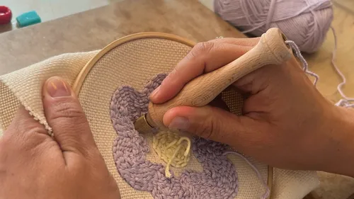 Hands embroidering with lavender thread in hoop.