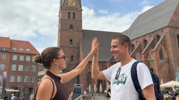 Zwei Personen geben High-Five vor Kirche.