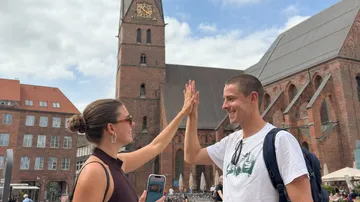 Zwei Personen geben High-Five, Kirche im Hintergrund