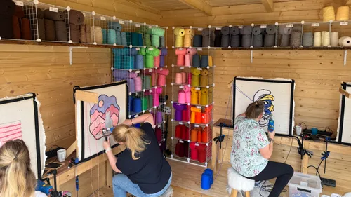 Women creating art with yarn in workshop.