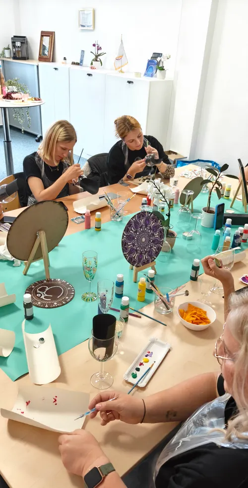 People painting glassware at crafting table.
