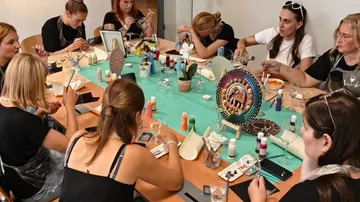 Menschen bemalen Glaswaren am Tisch.