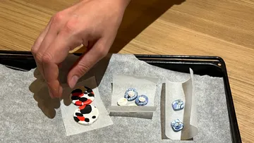 Hand placing paper on tray with crafted circles.
