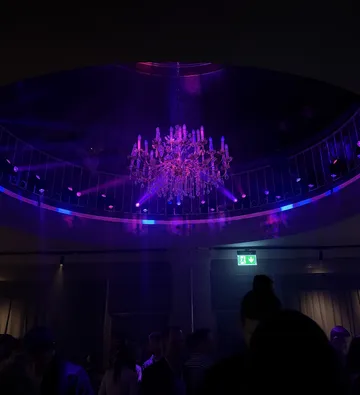 Chandelier lighting up a dark party venue.