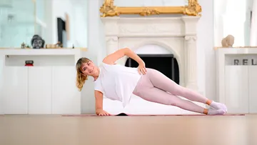 Frau macht Plank auf einer Yogamatte.