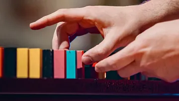 Hands arranging colorful domino blocks.
