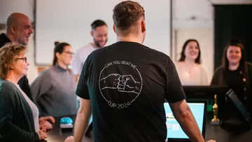 Group gathered, man with black shirt facing away.