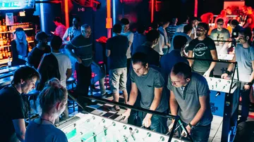 People playing foosball in a crowded bar.