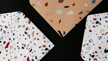 Bunte Terrazzo-Umschläge auf schwarzer Oberfläche.