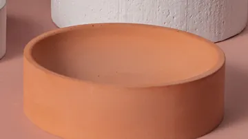 Terrakottaschale auf rosa Oberfläche.