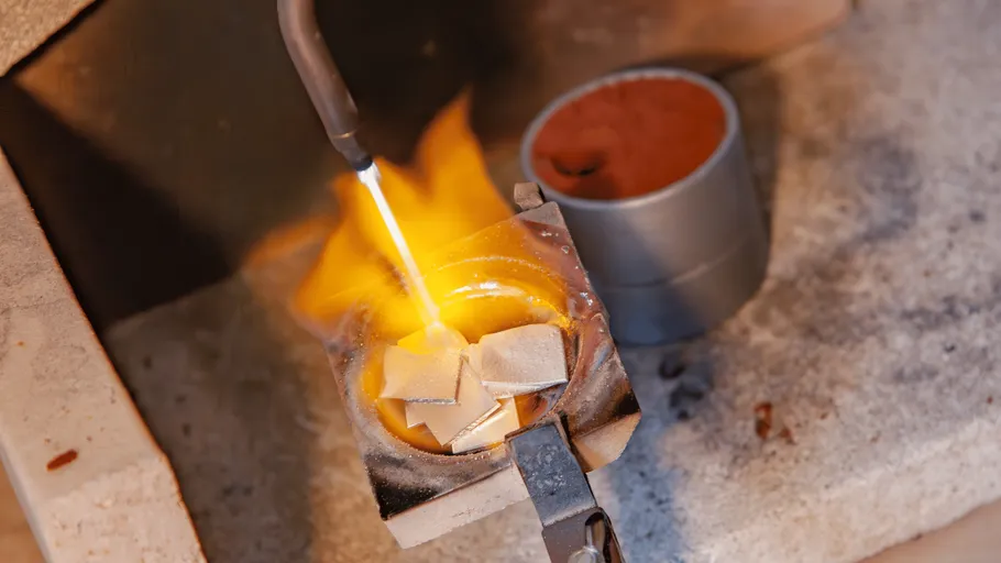 Metal pieces being melted with a torch flame.