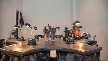 Jewelry workbenches with tools and lamps.