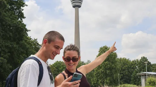 Menschen lächeln, zeigen auf einen großen Turm.