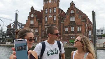 Menschen lächeln vor historischem Gebäude.