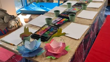 Kunstmaterialien auf einem Tisch in sonnigem Raum.