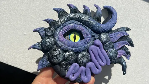Hand holds a mystical eye sculpture outdoors.