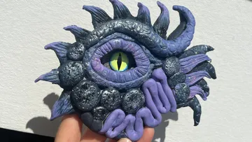 Monster eye sculpture held against wall.