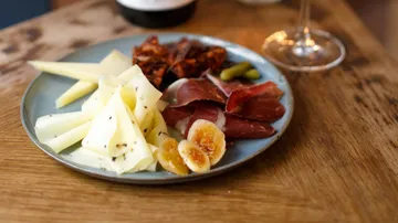 Plate with cheese, meats, figs on wood table.