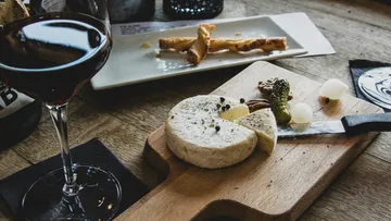 Käse auf Brett mit Weinglas.
