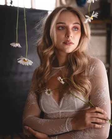 Frau mit Gänseblümchen in elegantem Raum.